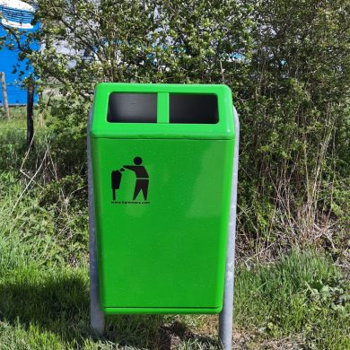 groene afvalbak, staat in het gras/ in de openbare ruimte 