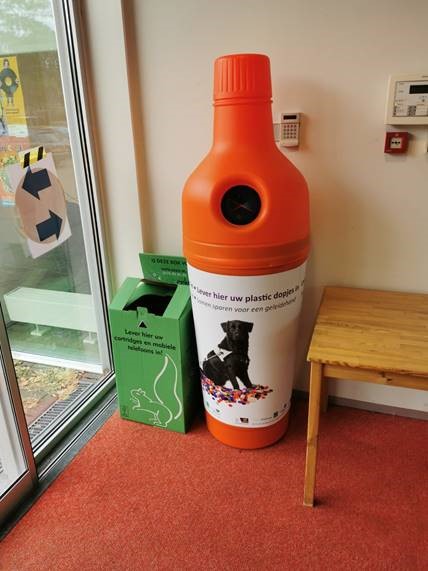 oranje plastic ton bij De Nieuwhof (vorm van een fles) om plastic doppen in te leveren voor KNGF Geleidehonden
